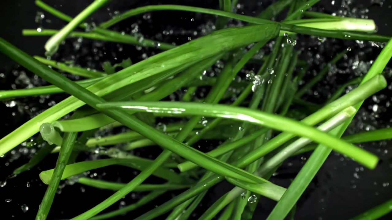 Super slowmotion af vand, der sprøjter på friske grønne purløg
