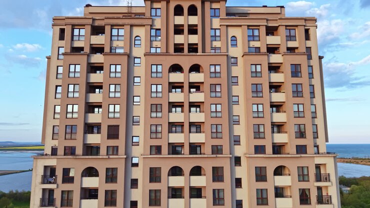 Un edificio si erge imponente in riva all'acqua, sotto un cielo azzurro con nuvole, di giorno, in un'area urbana.