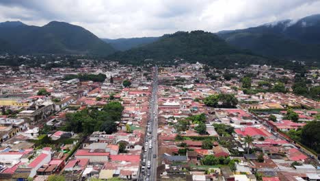 4k aerial drone footage of antigua, guatemala, with the cityscape and colorful buildings set against a backdrop of stunning mountains