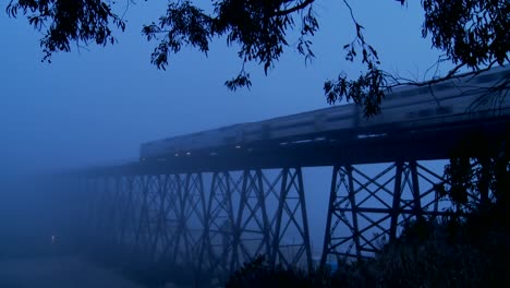 一列amtrak客運列車在夜晚在霧中穿過一座橋