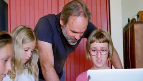 Father-and-daughters-using-laptop-in-kitchen-4k