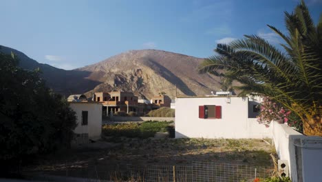 Wide-Shot-of-a-White-Building-with-a-Large-Mountain-In-The-Background-and-a-Palm-Tree