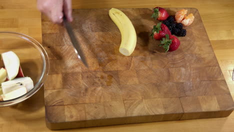 Cutting-and-peeling-banana,-trimming-and-cutting-strawberries-for-fruit-smoothie