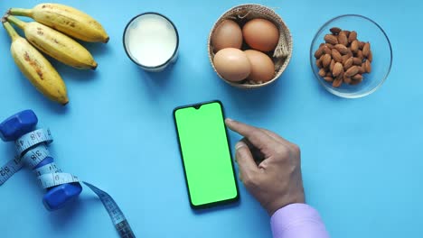 smart phone with empty screen , eggs , milk and almond nut in table