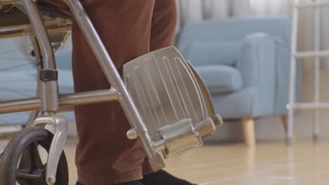 un close-up de un enfermero masculino sosteniendo la mano de un paciente que está en una silla de ruedas para levantarse y caminar durante una terapia física en casa