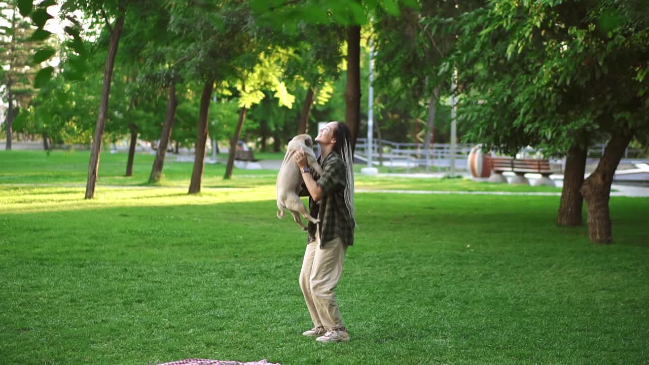 la chica y el perro se están divirtiendo, ella lanza el perro en el aire en el parque