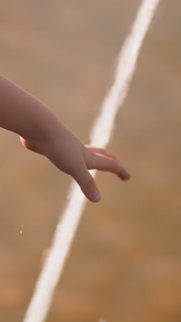 little girl hand touches powerful fountain water jet on city street close view slow motion. refreshing during hot summer day. child enjoys splashing water