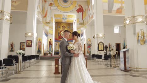 Hermosa-Pareja-De-Recién-Casados-Abrazando-Al-Novio-En-Una-Antigua-Iglesia,-Ceremonia-De-Boda,-Matrimonio