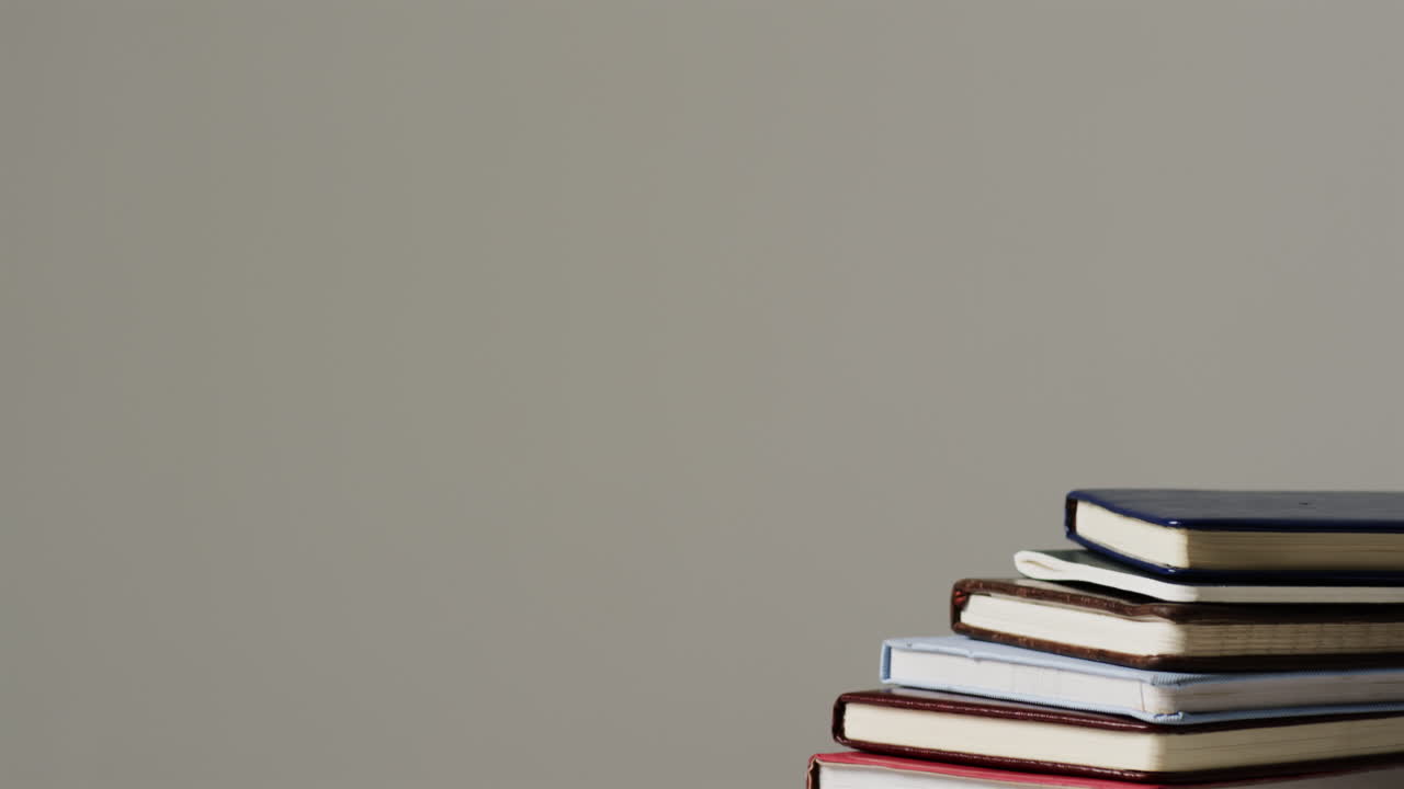 una pila de libros de tapa dura se coloca contra un fondo neutral, con espacio para copiar