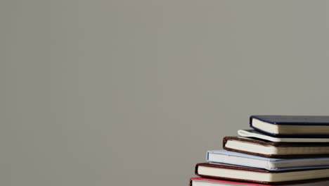 A-stack-of-hardcover-books-is-placed-against-a-neutral-background,-with-copy-space