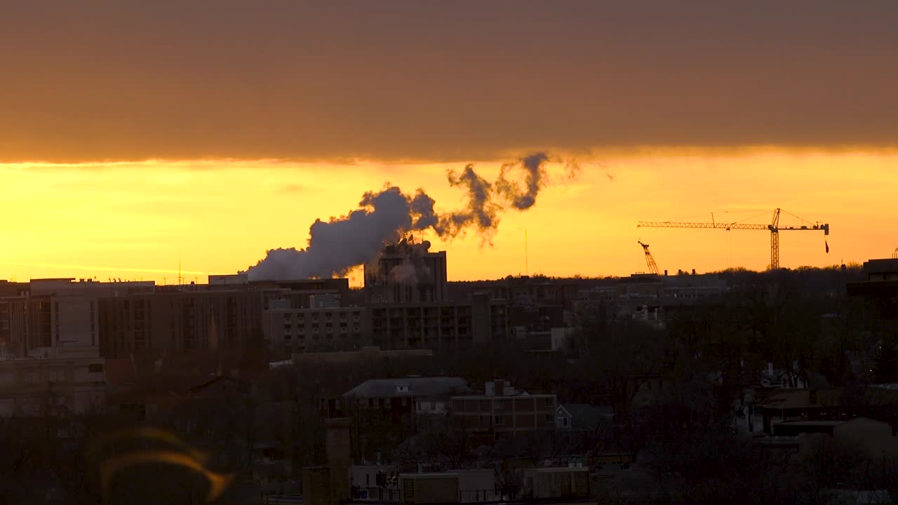 A distant shot of steam billowing against an orange sky