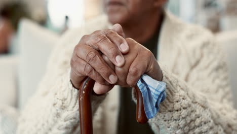 close up of an elderly man's hands resting on a cane