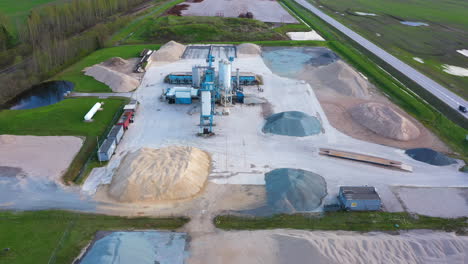 massive piles of raw material and industrial machines for asphalt making, aerial view