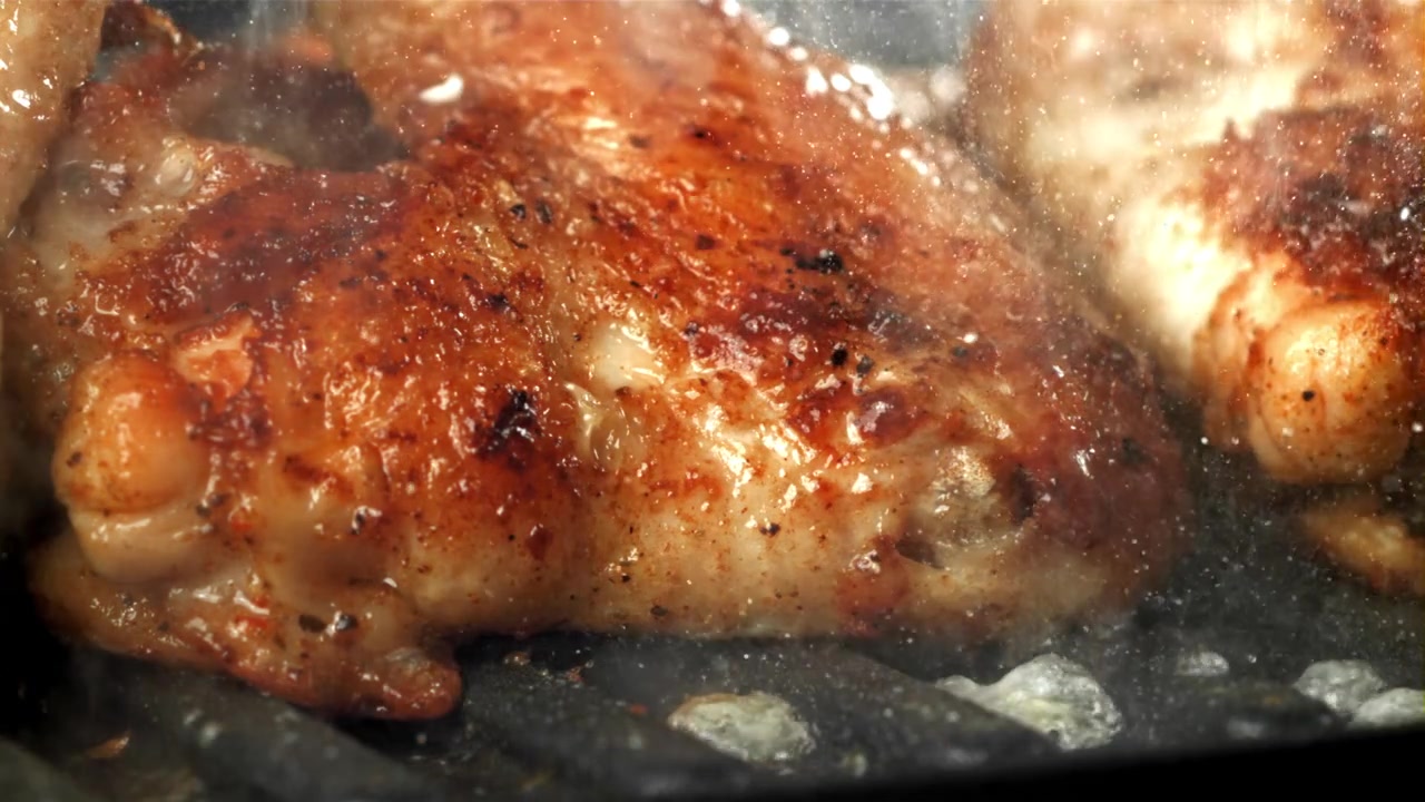 Ali di pollo dorate che sfrigolano su una piastra calda