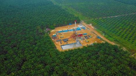 Cinematic-Drone-Shot-of-Onshore-Drilling-and-Workover-Rig-structure-and-Rig-equipment-for-oil-exploration-and-exploitation-in-the-middle-of-jungle-surrounded-by-palm-oil-trees-during-sunset-time