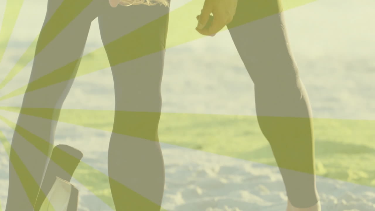 Surfers standing on beach shore for travel marketing wearing wetsuit leggings showing radial stripe