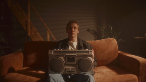 portrait of young man inserting cassette tape into retro boombox