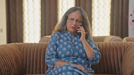 tensed indian old woman talking on a phone call