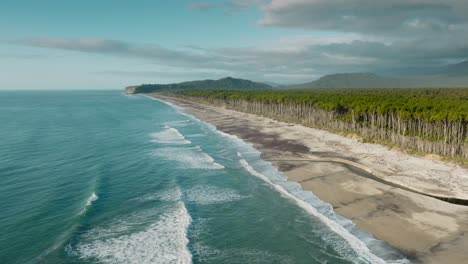 vista aérea del vasto, salvaje, accidentado y remoto paisaje de la bahía de bruce con playa de arena, bosque de árboles de rimu nativos y montañas en la distancia, sur de westland, nueva zelanda aotearoa