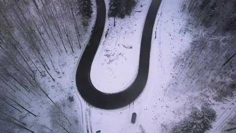 Rotation-and-ascending-over-curved-road-in-snowy-woodland,-Black-Forest-Germany