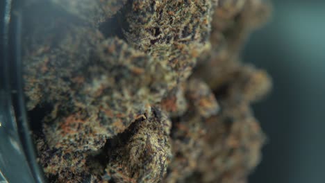 a vertical macro cinematic detailed shot of a cannabis plant, orange hybrid strains, indica and sativa ,black marijuana flower, on a rotating stand, slow motion, 4k video, professional studio light