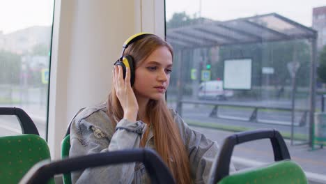 Young-woman-wearing-headphones-listening-music,-funny-relax-dancing-while-traveling-by-bus-to-city