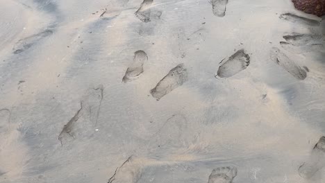 an indian girl walking briskly near her foot mark in a beach