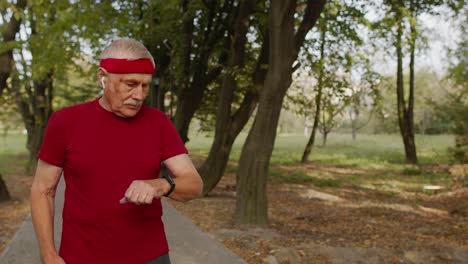 Deportista-Senior-Iniciando-El-Cronómetro-De-Reloj-Inteligente,-Rastreando-La-Distancia-Y-Comenzando-A-Correr-En-Un-Parque-Público