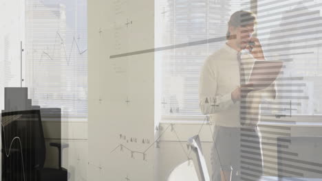 mid adult man using smartphone while holding laptop in modern office, with animated business charts