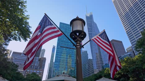 two american flags on lamppost in bryant park, modern skyscrapers with blue sky in background, new york city, usa