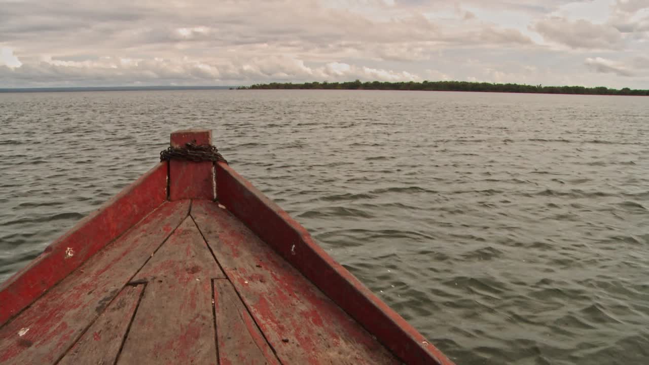 mirando por encima de la proa de un barco de madera mientras navega por el río amazonas en brasil