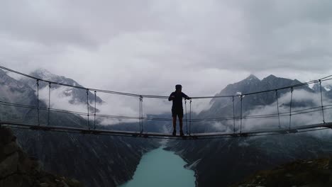 thrilling slow motion shot of man jumping on narrow bridge above dramatic valley