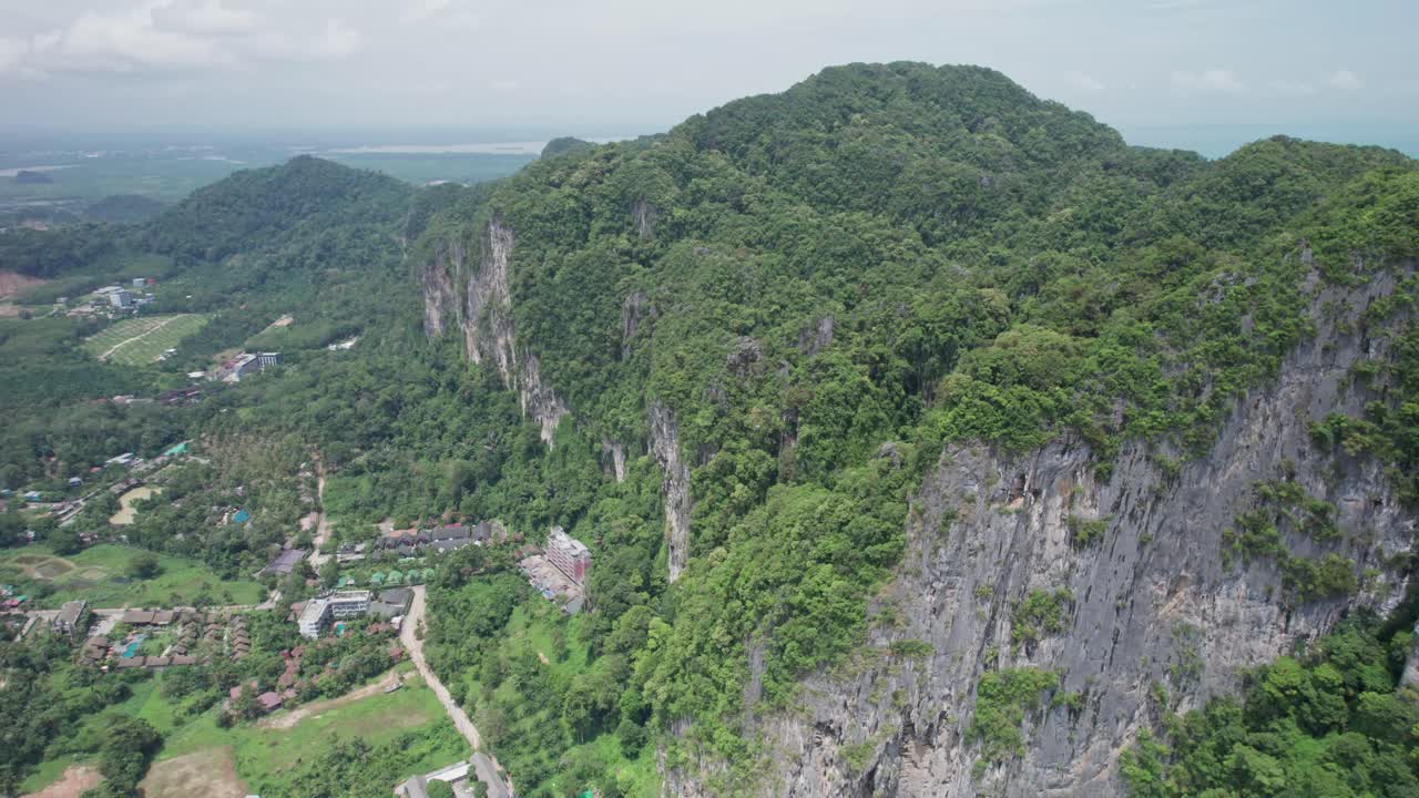 A towering limestone karst dominates the lush terrain in this drone shot from Thailand