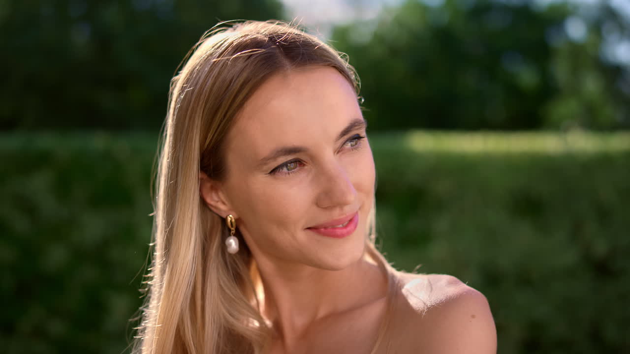 Přitažlivá žena drží ruku na bradě. Jemná dáma flirtuje s kamerou venku.
