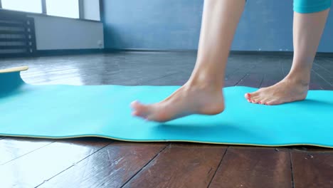woman sitting in yoga pose on a teal yoga mat