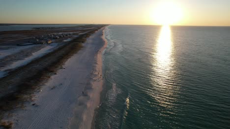 drone flying thou dunes with sea oats at sunrise to the white sand beach clear emerald waters to view of the fishing pier on navarre beach