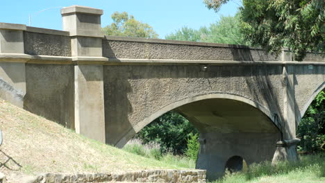 old historic cement arch bridge over river, pan right