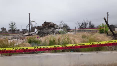 gimbal wide panning shot of fire debris cordoned off by caution tape after the palisades fire in los angeles, california. 4k
