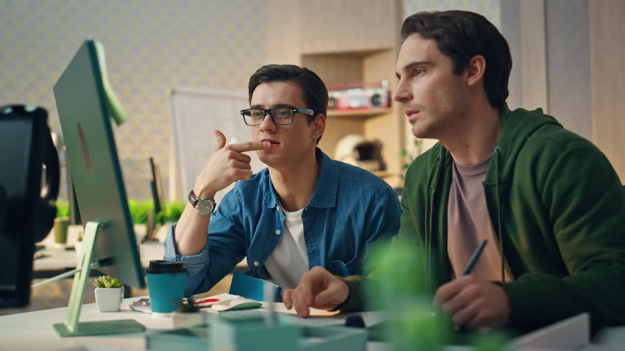 Focused colleagues staring computer screen at room. Creative men work together