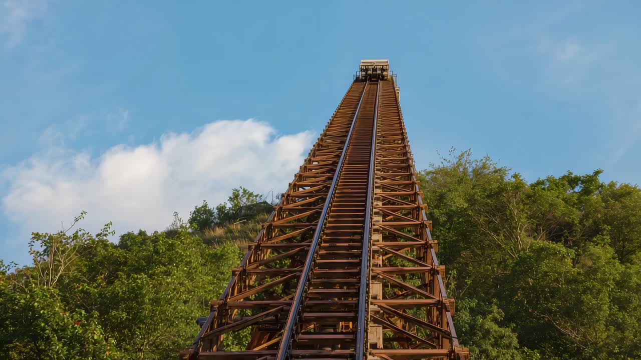 Lift-hill chain engaging coaster train climbing steel track on hillside, with riders raising arms