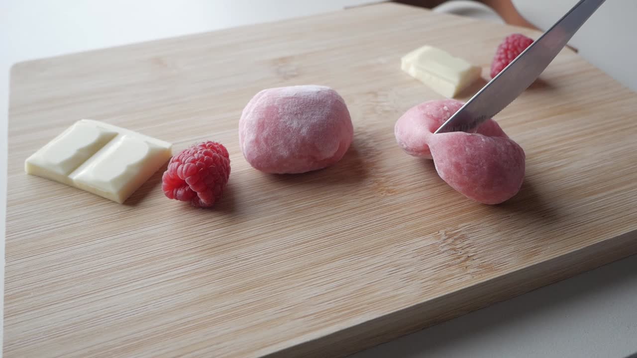 Soft pink mochi filled with strawberry and white chocolate, sliced for a close-up view