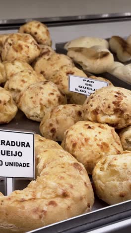 4k vertical close-up of a freshly made queijadinha, a traditional brazilian dessert, on display for sale. the golden texture and detail make it perfect for food, culinary, and market-themed visuals.