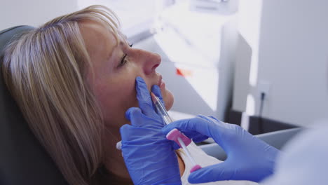 mature woman sitting in chair being give botox injection by female doctor