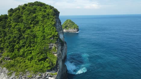 drone shot of limestone rocks with green trees in blue sea