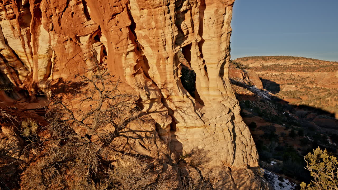 Aerial sunrise view of a hidden sandstone arch emerging from the rugged landscape near Kanab, Utah.