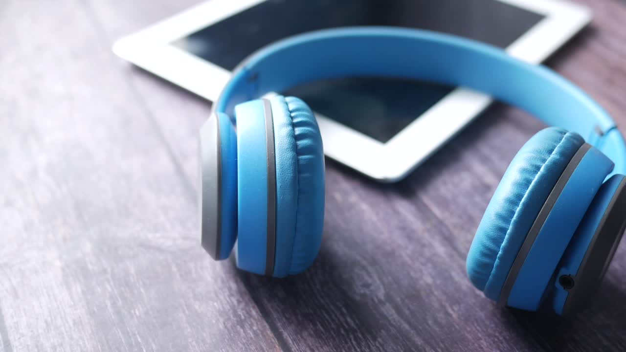 auriculares y tabletas azules en superficie de madera