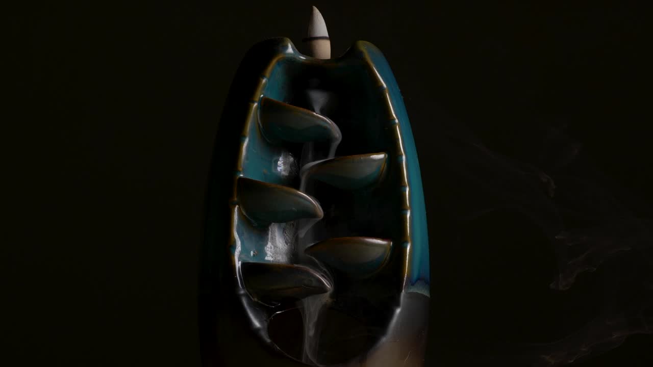 tiro sereno de incienso que fluye sobre un soporte de cerámica con fondo negro