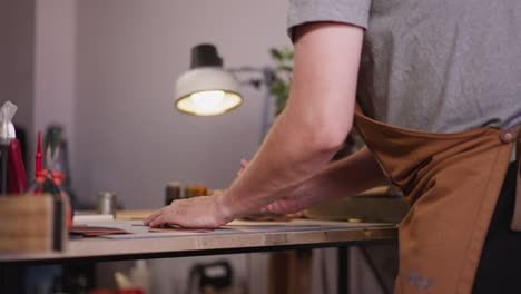 worker uses knife and ruler to cut leather at workplace