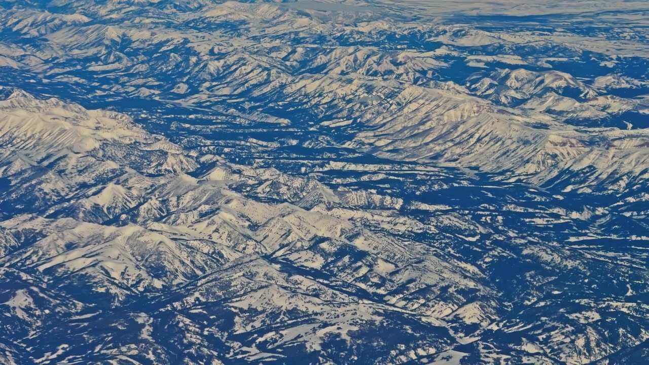 険しい荒野の風景に広がる、果てしなく続く雪をかぶった山々の空撮。