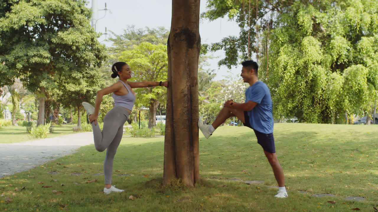Diverse Athletes Chatting when Stretching Legs Muscles in Park